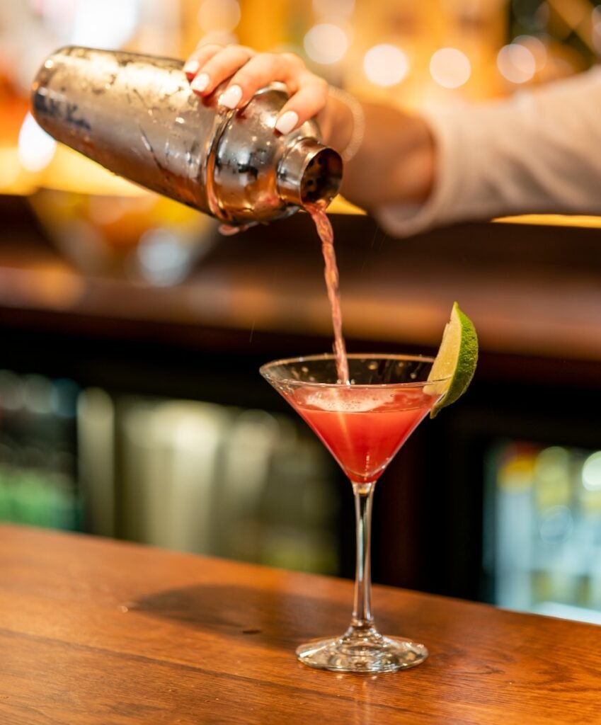 person pouring beverage on clear drinking glass